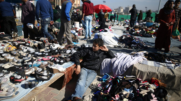 A Palestinian boy sits amidst used clothes and items at the weekly flea market in the Nusseirat Refugee Camp, central Gaza Strip, on February 29 (AFP photo)